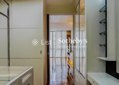 Interior hallway leading to another room with wooden flooring and glass shelves