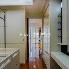 Interior hallway leading to another room with wooden flooring and glass shelves