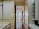 Interior hallway leading to another room with wooden flooring and glass shelves