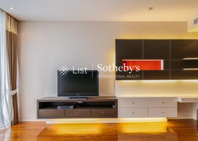 Modern living room with TV, wall-mounted shelves, and large window with curtains.