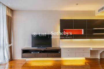 Modern living room with TV, wall-mounted shelves, and large window with curtains.