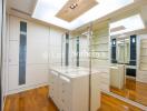 Walk-in closet with wooden floors and mirrored cabinets