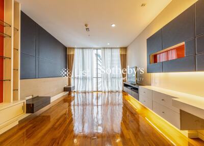 Modern living room with wooden floors, large window with curtains, built-in cabinets and shelves, and stylish lighting