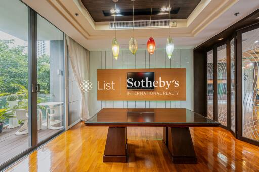 Modern conference room with a large dark wood table, colorful hanging lights, and a view of an outdoor patio