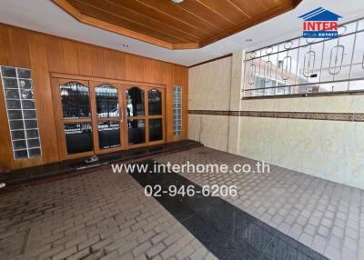 Exterior view of a tiled and partially wooden-paneled area with glass doors