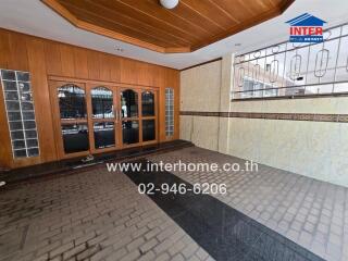 Exterior view of a tiled and partially wooden-paneled area with glass doors