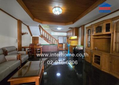 Living room with wooden cabinetry, staircase, sofa, and dining area