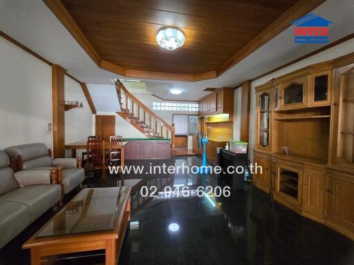 Living room with wooden cabinetry, staircase, sofa, and dining area