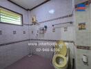 Bathroom with tiled walls, a toilet, a shower, and a small window