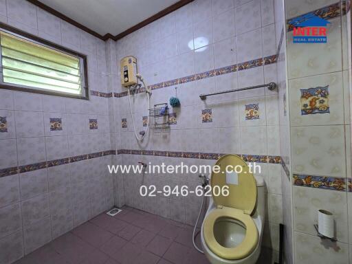 Bathroom with tiled walls, a toilet, a shower, and a small window