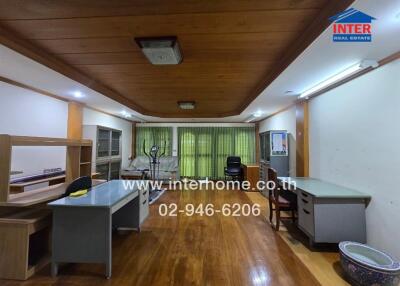 Office space with multiple desks and chairs, featuring a wooden floor and ceiling with overhead lights