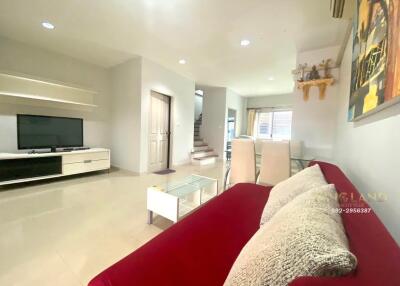 Modern living room with a wall-mounted TV, red sofa, and dining area