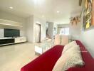 Modern living room with a wall-mounted TV, red sofa, and dining area