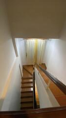 Staircase with wooden steps and a window with curtains