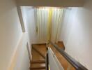 Staircase with wooden steps and a window with curtains