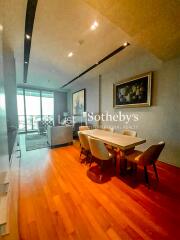 Modern living room with dining table and chairs, featuring wooden flooring and balcony view