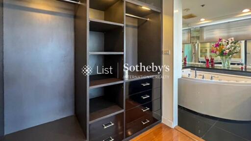 Spacious walk-in closet with built-in shelves and drawers, adjacent to luxurious bathroom