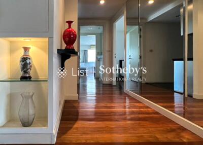 Well-lit hallway with decorative vases, wooden flooring, mirror wall, and built-in shelves