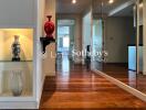 Well-lit hallway with decorative vases, wooden flooring, mirror wall, and built-in shelves