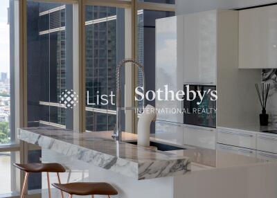 Modern kitchen area with marble countertops and large windows