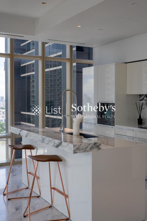 Modern kitchen area with marble countertops and large windows