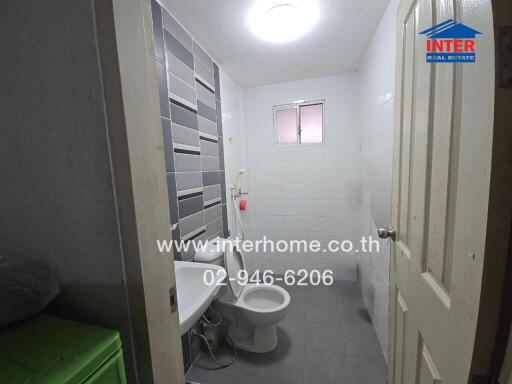 Bathroom with tiled walls, toilet, shower, and window