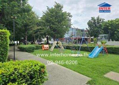 Community playground area with swings, slides, and greenery