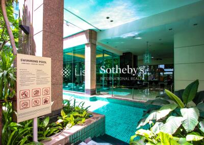 Photo of a swimming pool area with landscaping and building entrance.