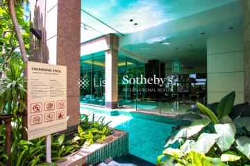 Photo of a swimming pool area with landscaping and building entrance.