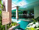 Photo of a swimming pool area with landscaping and building entrance.