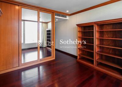 Spacious bedroom with wooden flooring, built-in mirror door wardrobe, and wall-mounted air conditioning.