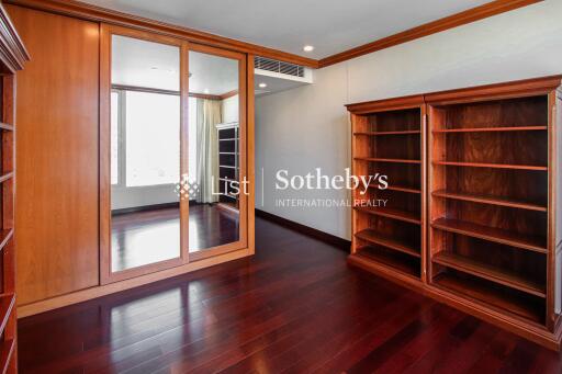 Spacious bedroom with wooden flooring, built-in mirror door wardrobe, and wall-mounted air conditioning.