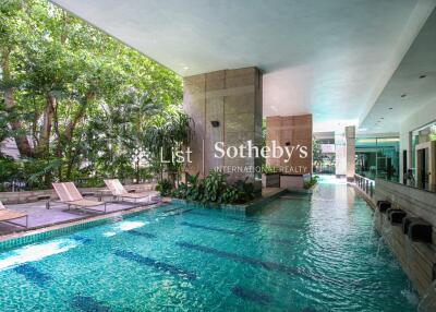 Indoor swimming pool with lounging chairs and greenery