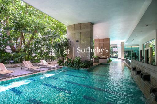 Indoor swimming pool with lounging chairs and greenery