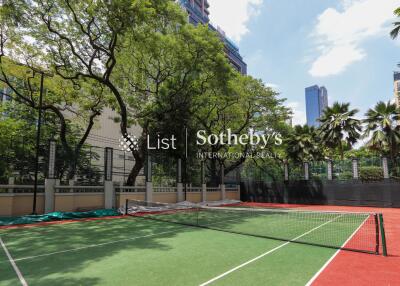 Outdoor tennis court with trees and high rise buildings