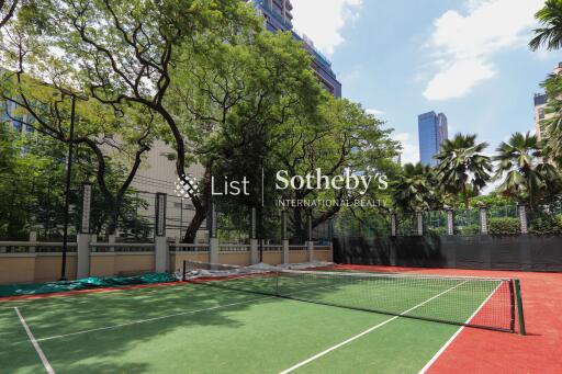 Outdoor tennis court with trees and high rise buildings