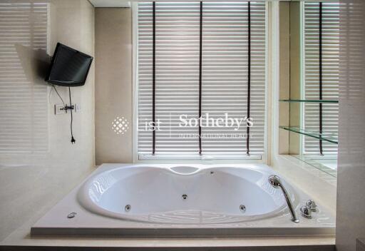 Modern bathroom with a large bathtub and wall-mounted TV