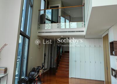 Modern duplex living area with high ceilings and staircase