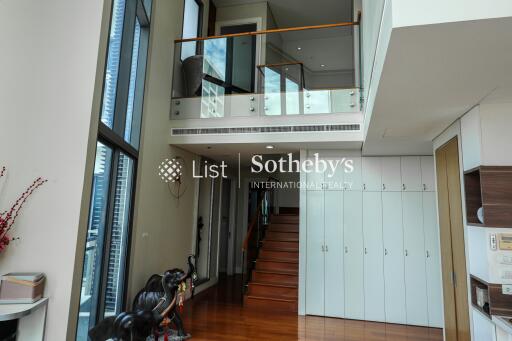 Modern duplex living area with high ceilings and staircase