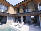 Modern outdoor lounge area with pool and view of interiors