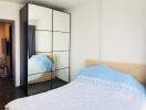 Bedroom interior with a bed, mirrored wardrobe, and window