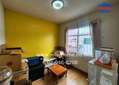 Small cluttered room with yellow wall and window