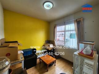 Small cluttered room with yellow wall and window