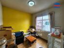 Small cluttered room with yellow wall and window