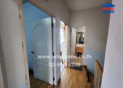 Hallway with doors leading to different rooms, featuring wooden flooring.