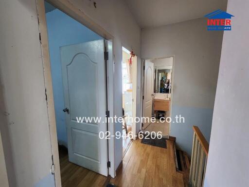 Hallway with doors leading to different rooms, featuring wooden flooring.