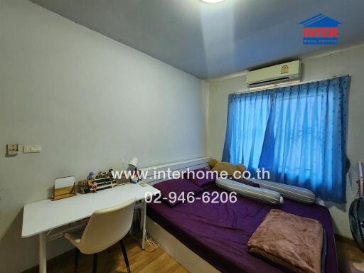 Bedroom with bed, desk, and window with blue curtains