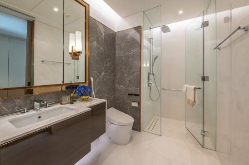 Modern bathroom with glass shower, toilet, and double sink