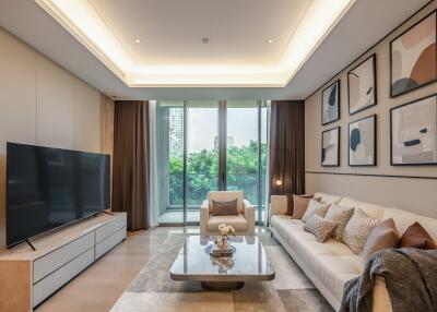 Modern living room with a large TV, sofa, coffee table, and artwork on the wall