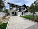 Front yard view of a residential building with garden and tiled pathway